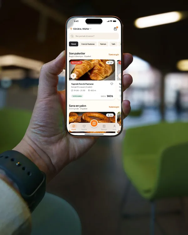 Kafede elde tutulan iPhone’da Ye Gitsin Keşfet ekranı